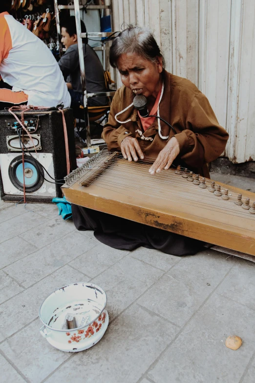 an elderly woman playing a musical instrument on the street