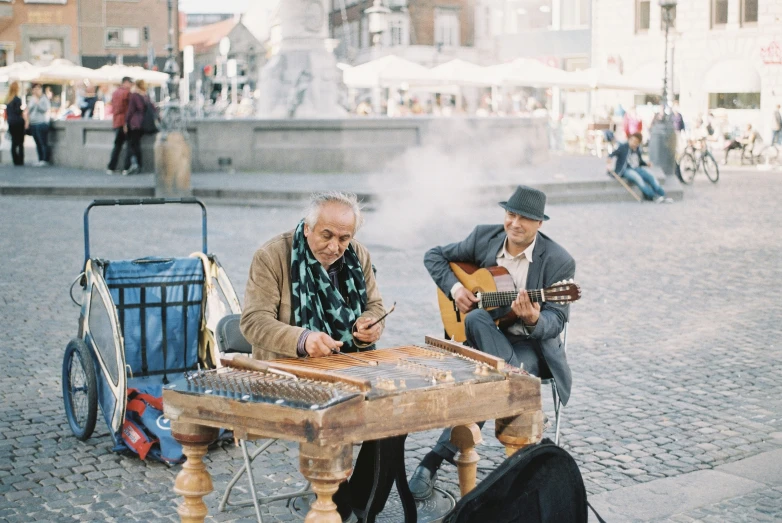 two men playing music on a small wooden table