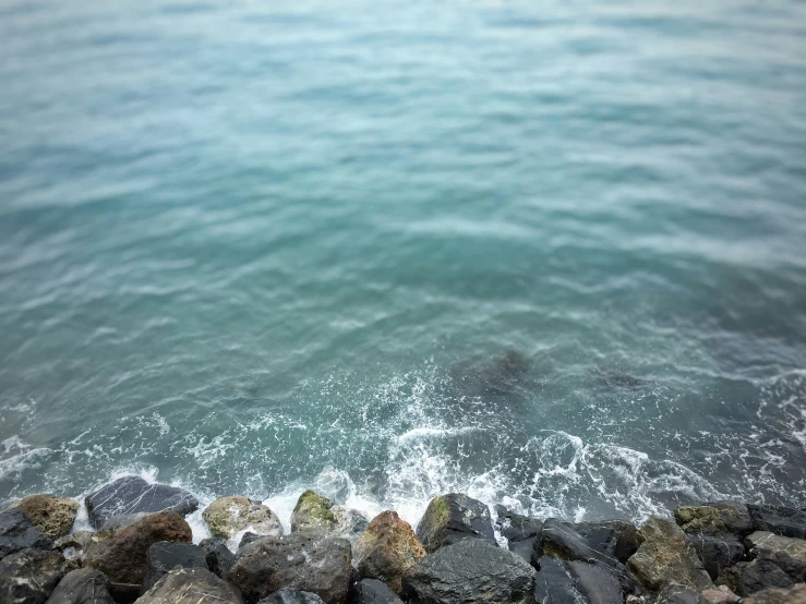 a man is standing on rocks near the ocean