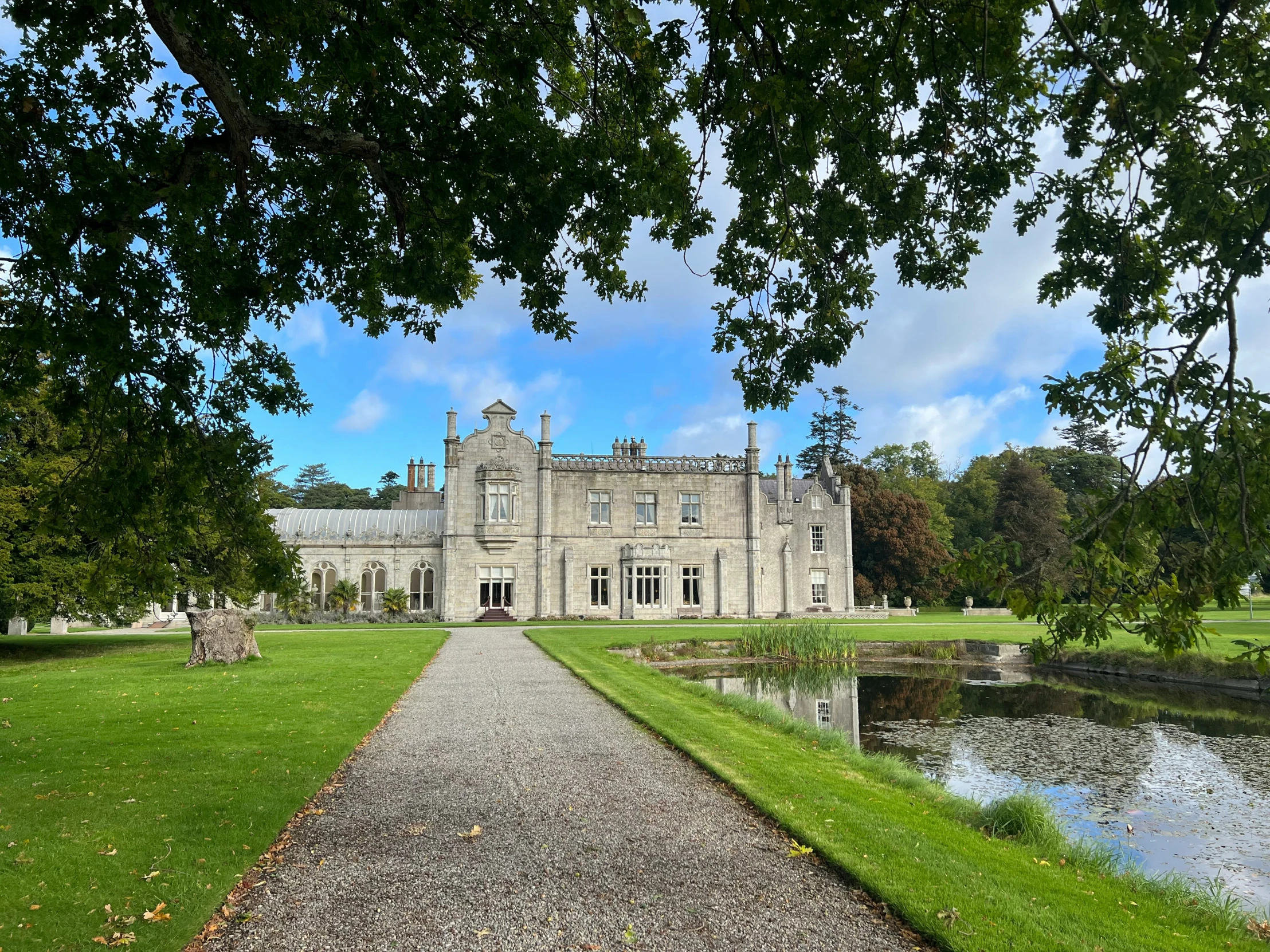 a view of a large mansion with pond behind it