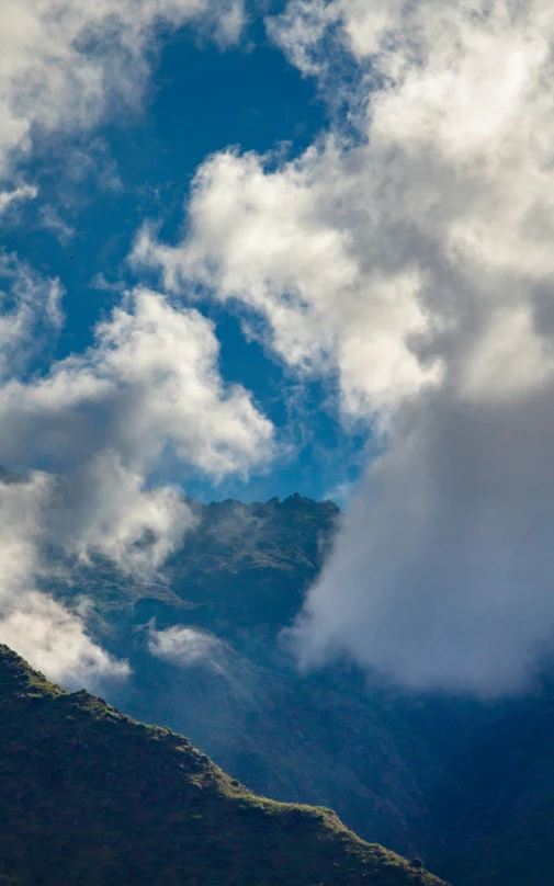 a plane flying in the sky above a green mountain side