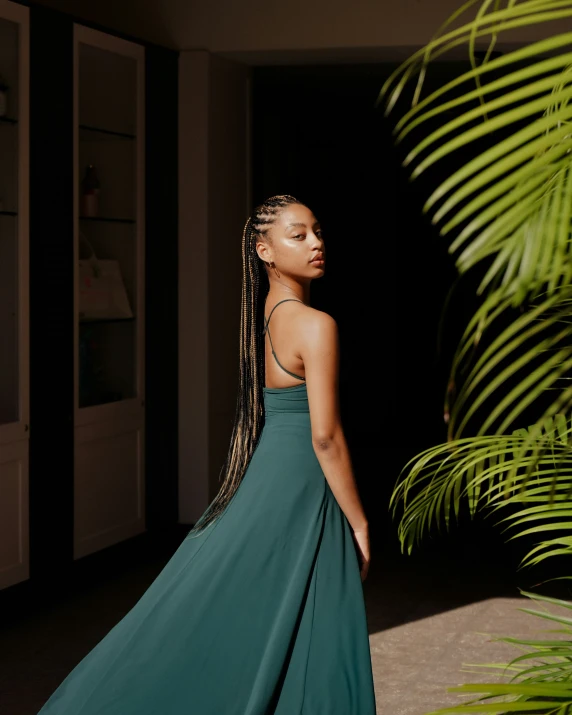 a  wearing a green dress standing next to a palm tree