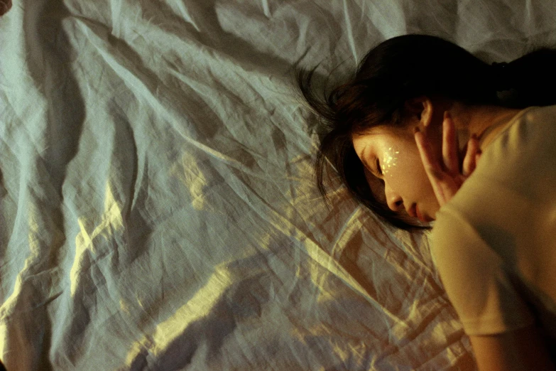 a woman sleeping on a bed with her hand under her chin