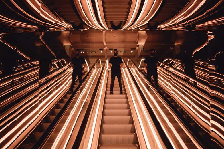 several people standing on an escalator with some moving lights