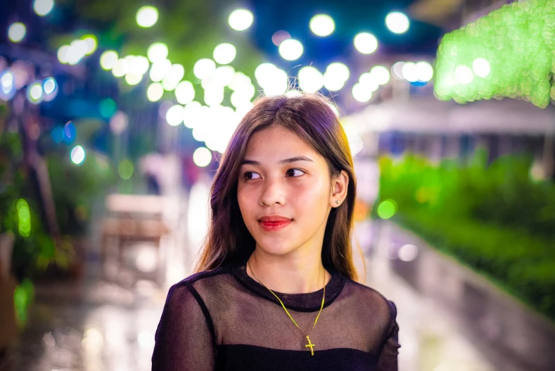 woman in black top standing on side of street at night