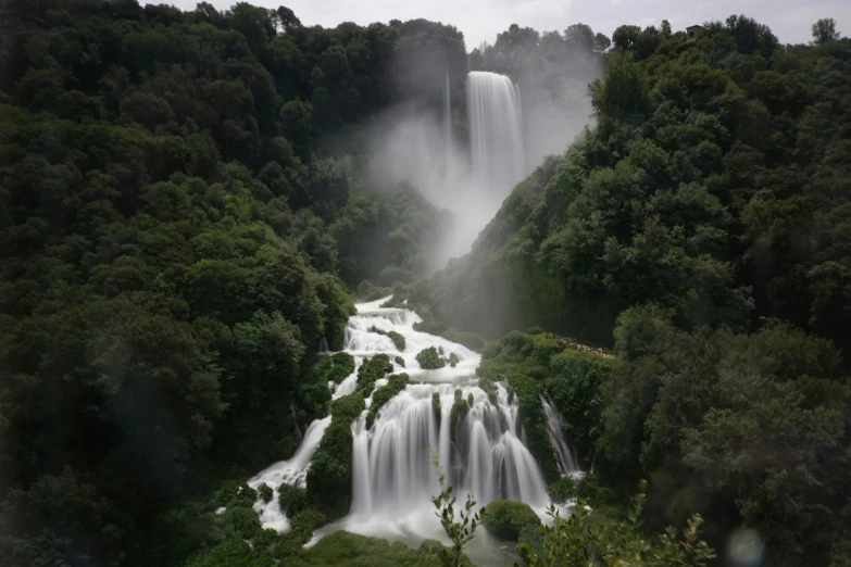 a waterfall with mist coming out the top and water below it