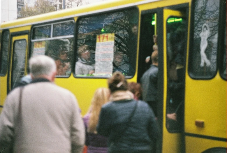 a group of people getting on to a yellow bus