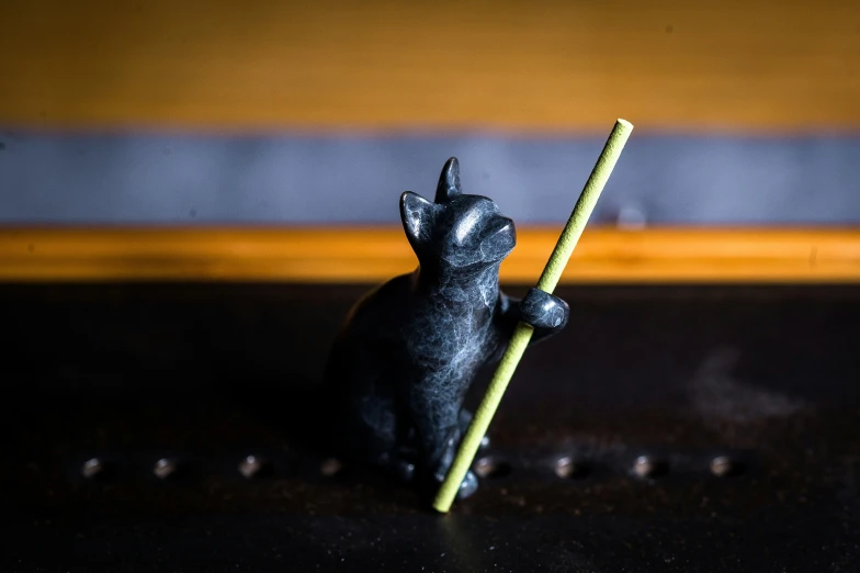 a black figurine sitting on top of a table holding a stick