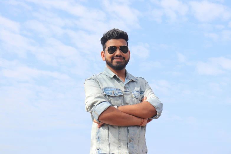 a man in denim shirt and sunglasses on a beach