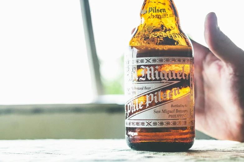 someone holding a bottle on the table with a blurry background