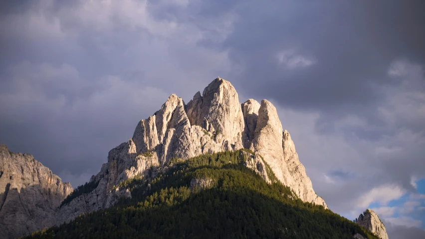 mountains rise above the forest and under a cloudy sky