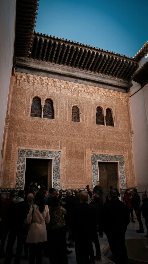 several people standing outside of an old building with a clock on the wall