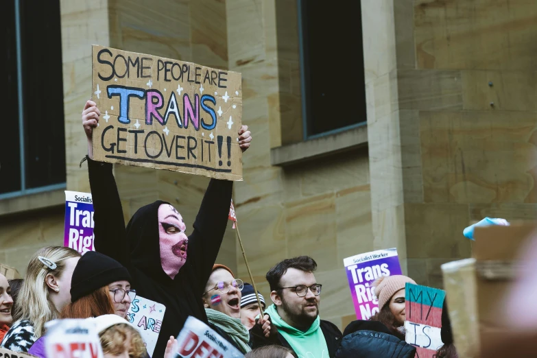 many protesters gathered outside a building with signs