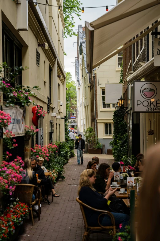 many people sitting around tables in a narrow alley