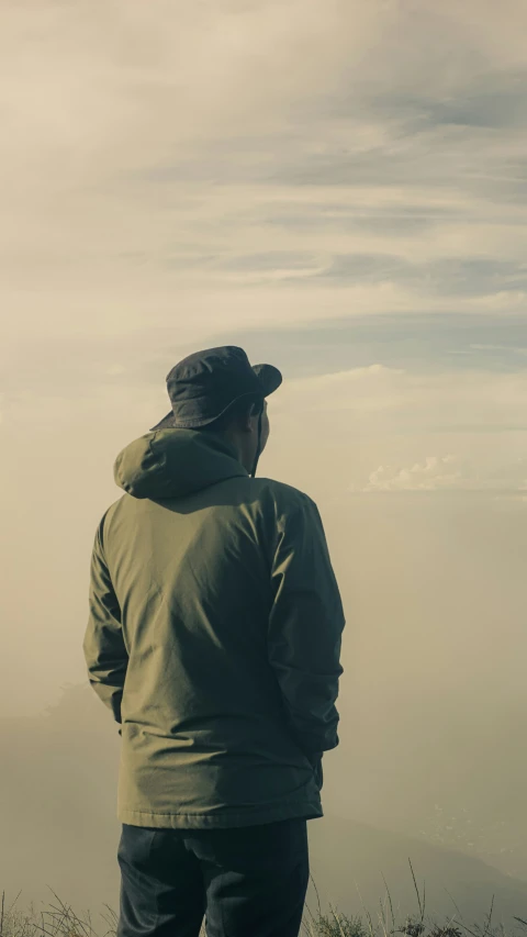 a man standing in the fog on top of a hill