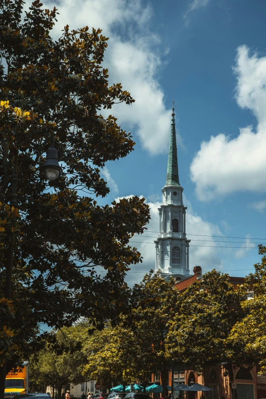 people walking on the sidewalk in front of trees and buildings