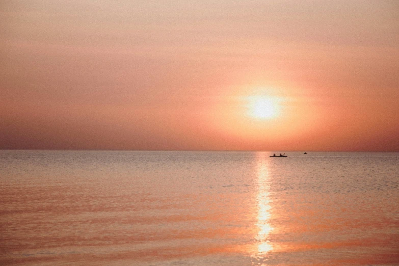 a boat out in the ocean at sunset