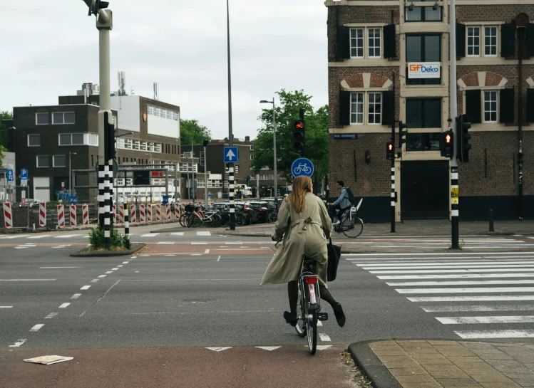 a woman riding a bike down a street next to a traffic light