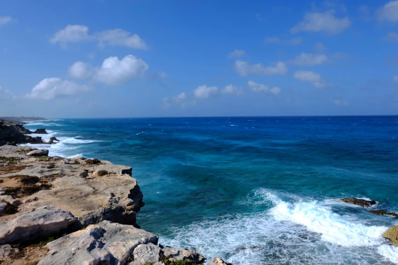 waves crashing into the water at the edge of a rocky coast