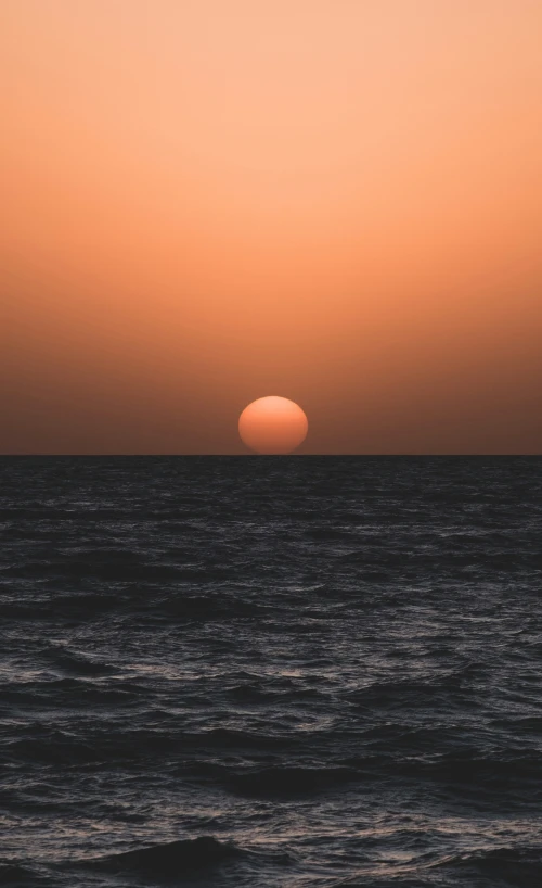 an orange sunset over the ocean with waves