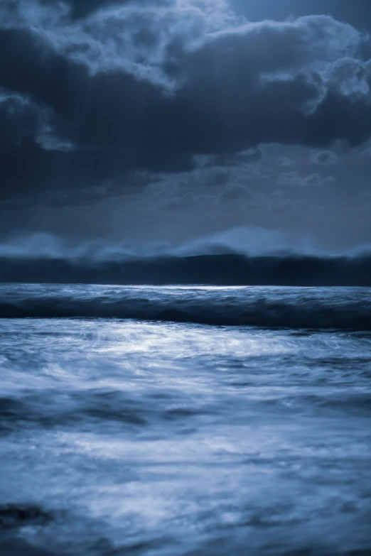 a bright blue ocean under dark clouds at night