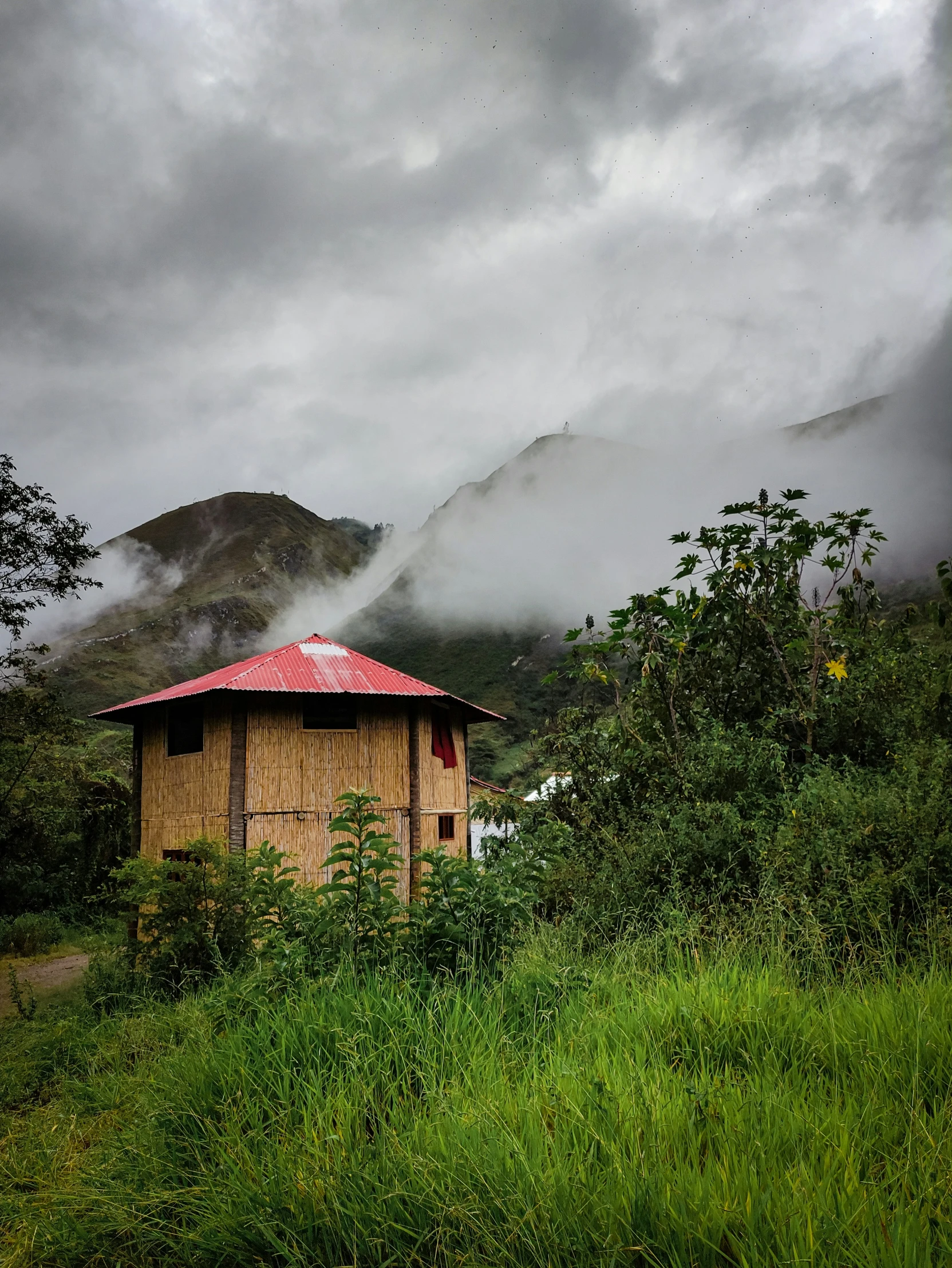 a red hut sitting on top of a lush green hillside