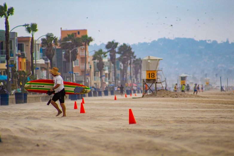 two people are carrying surfboards at the beach