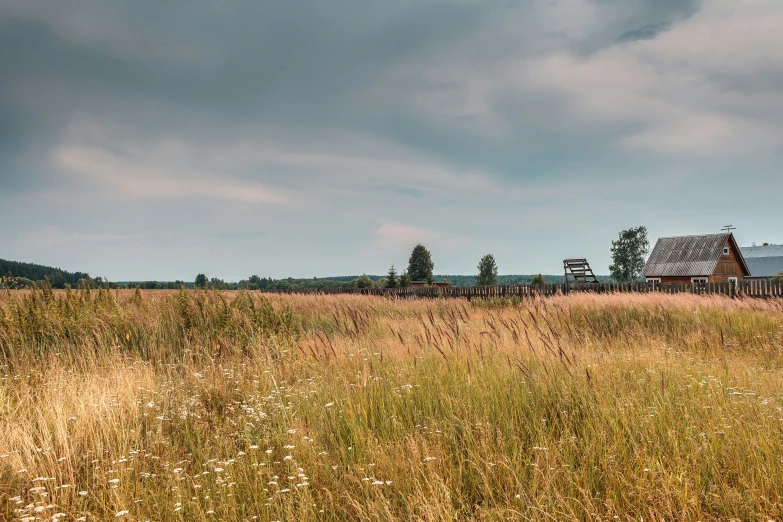 an old farm house on a grassy plain under dark skies