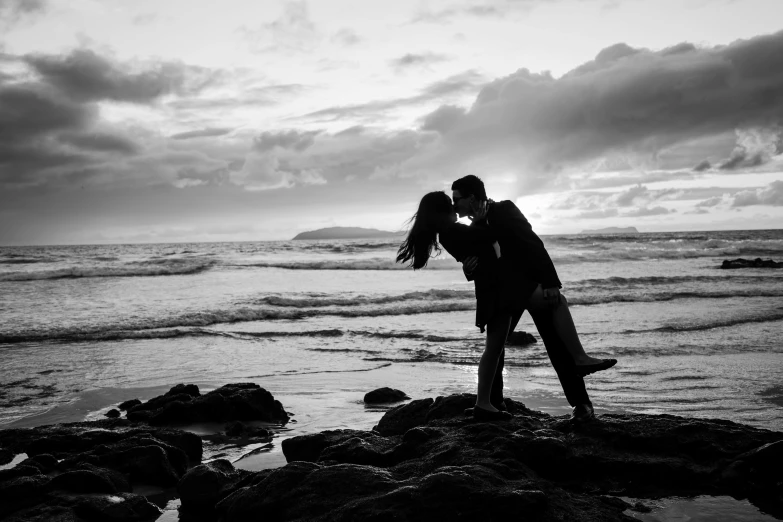 an image of a man standing on the beach kissing another man