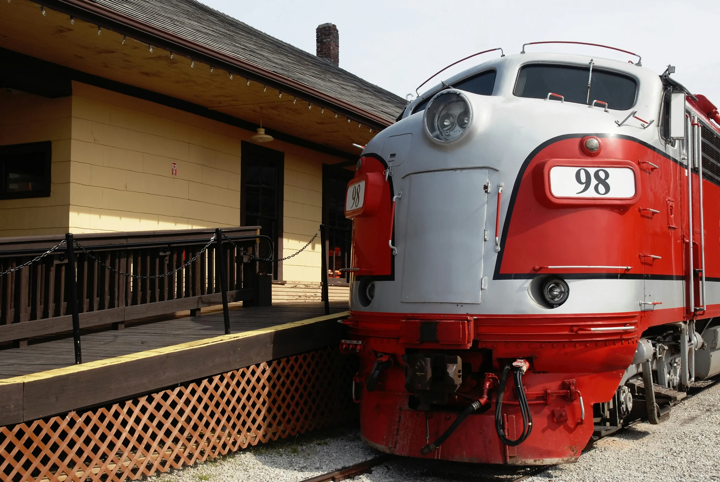 a red and white train parked next to a building