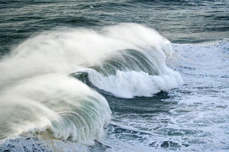 a big wave crashes near the shore of an ocean