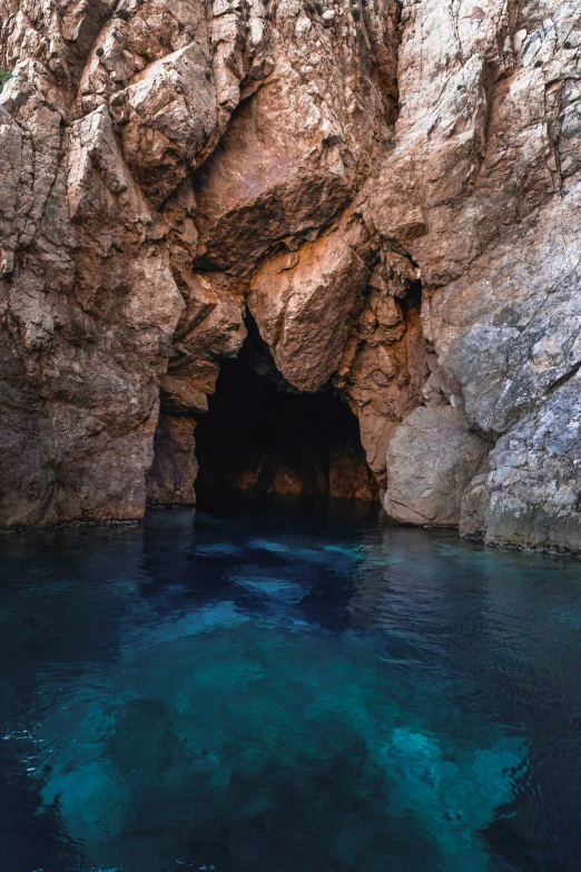 a rocky cliff with blue water near the entrance to it