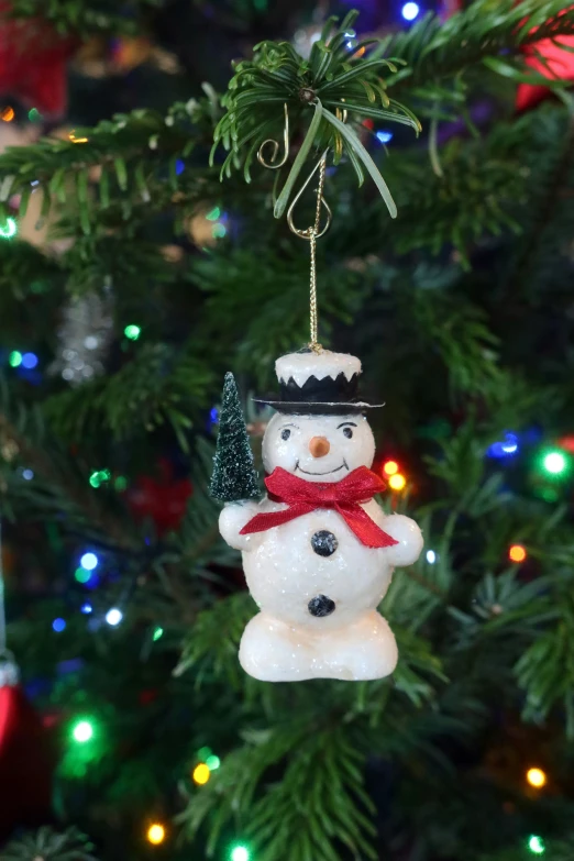 a snowman ornament is hanging from a tree