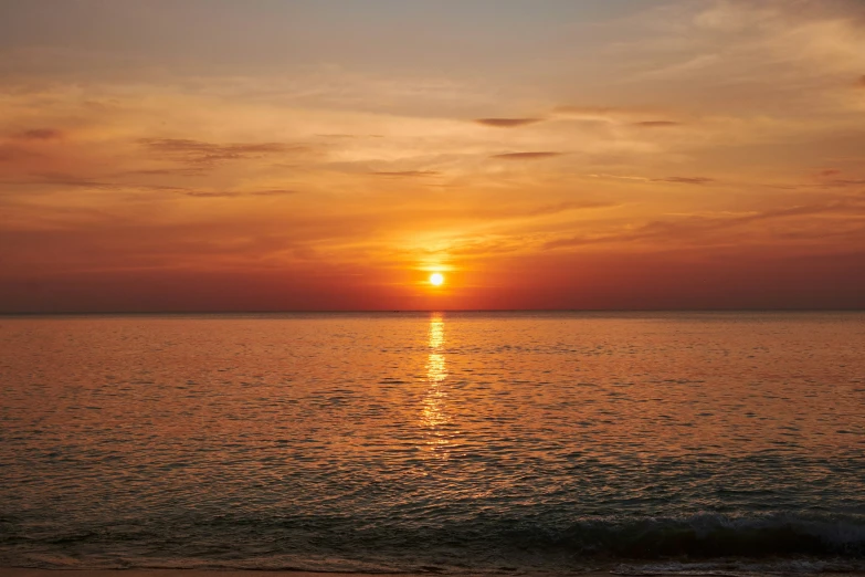 the sun rising over the water on the beach