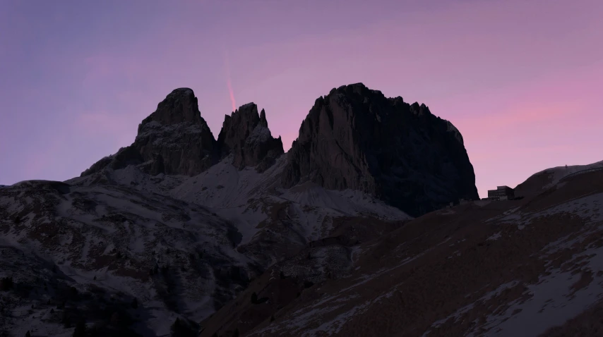 the top of two mountains with a pink sky