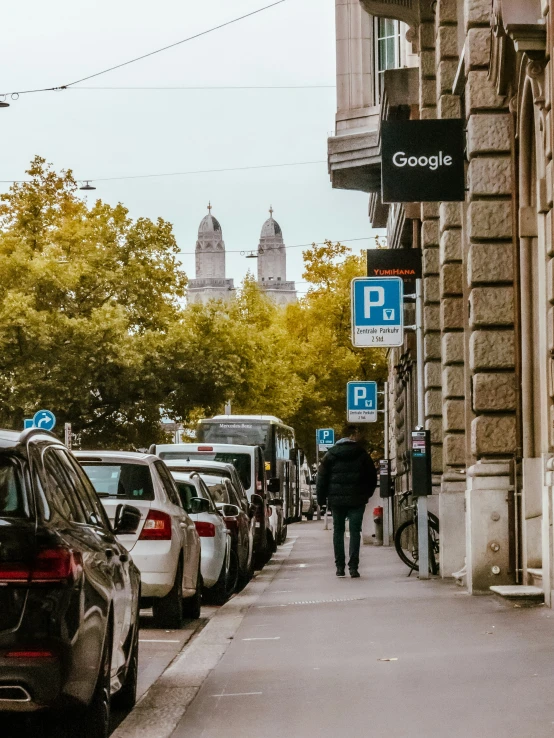 a man walking down the sidewalk past many parked cars