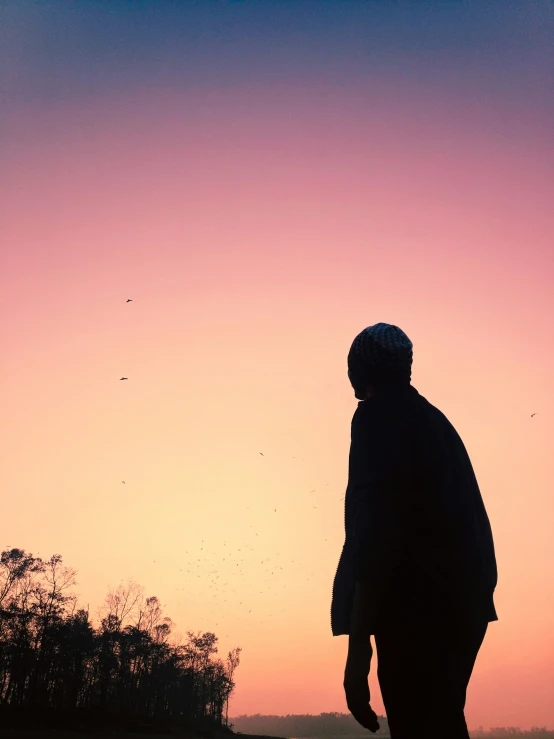 a silhouette of a person on a hill in the evening