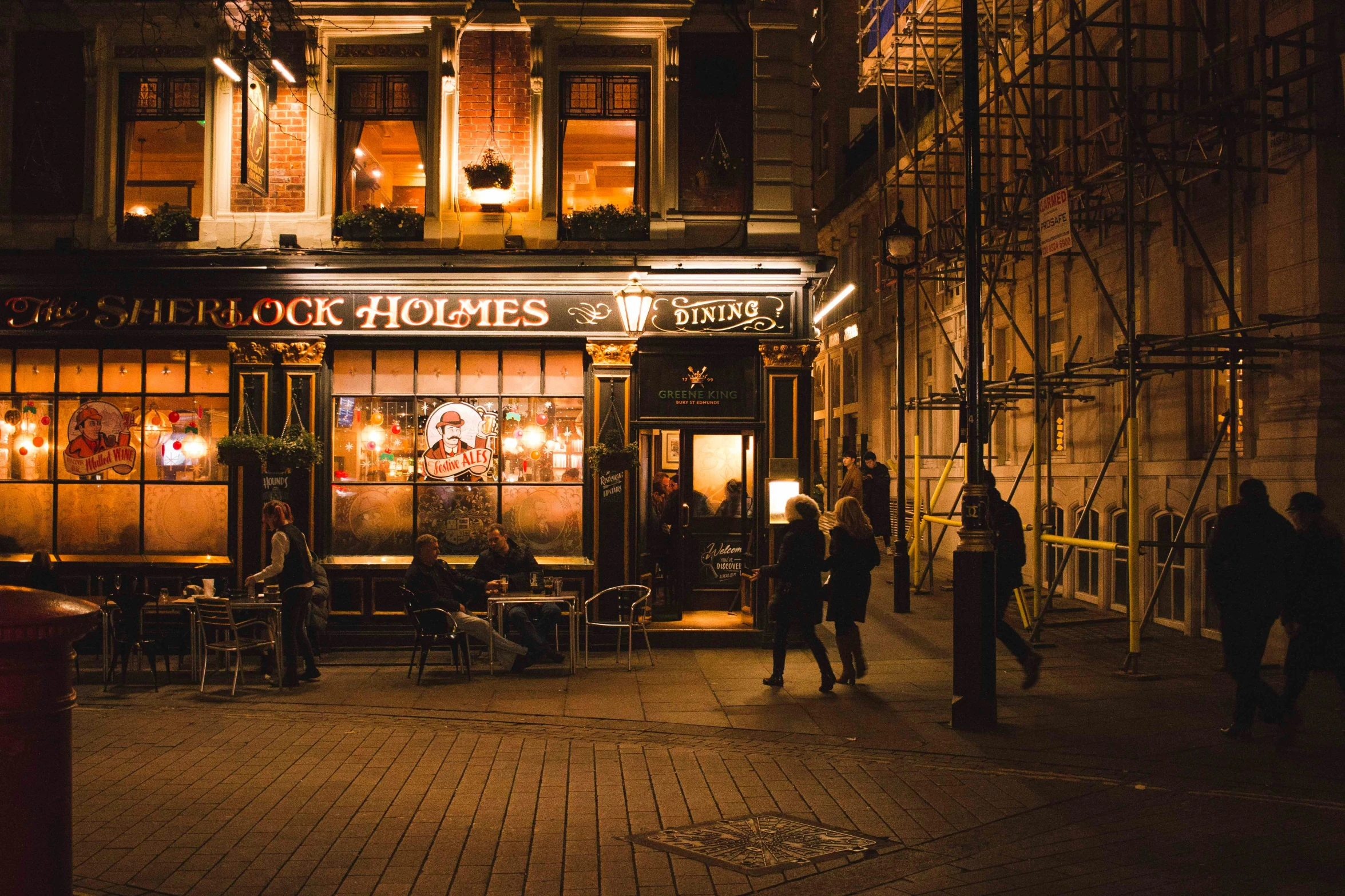 people are walking in front of a restaurant at night