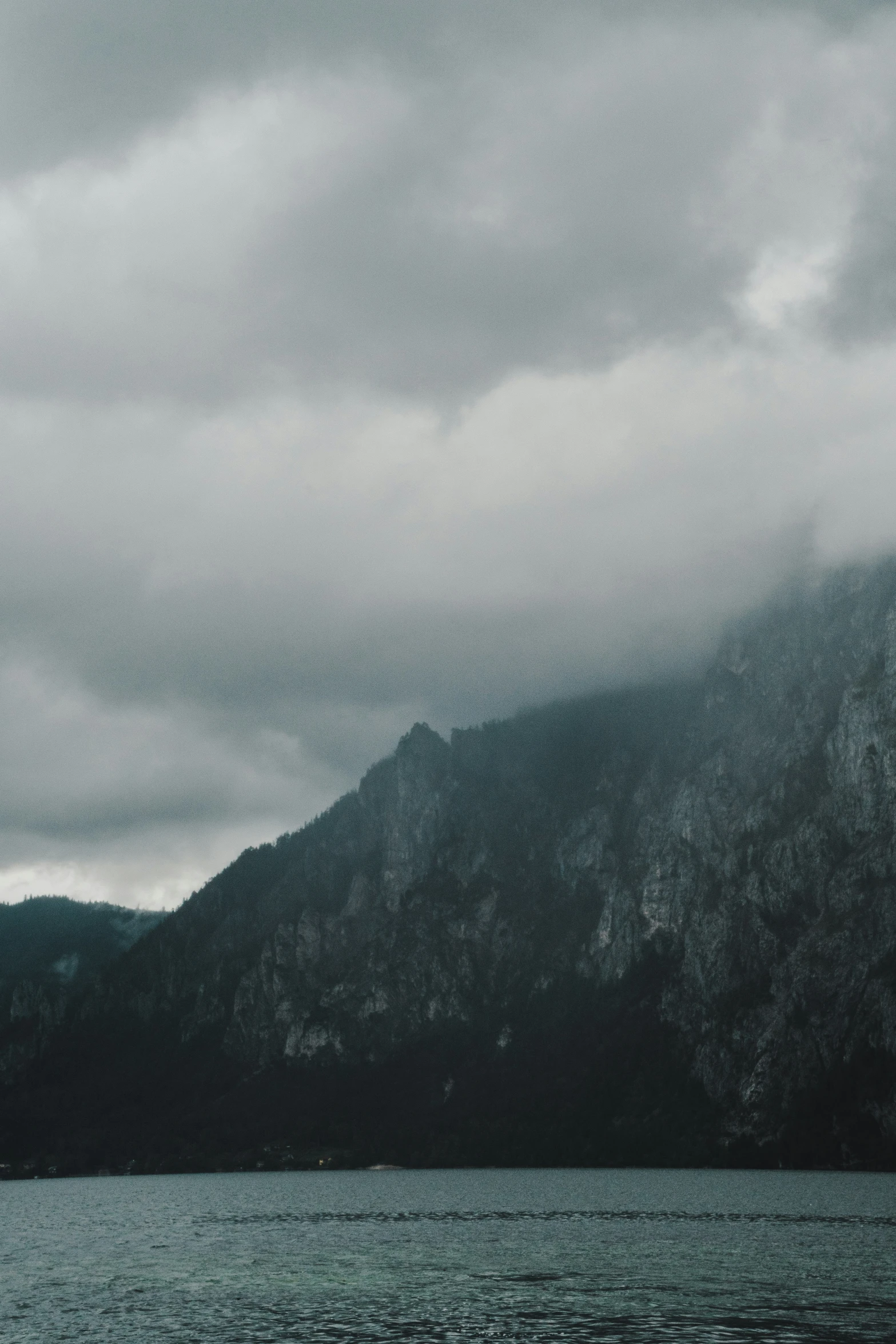 the mountains are in the dark with some clouds hanging over them