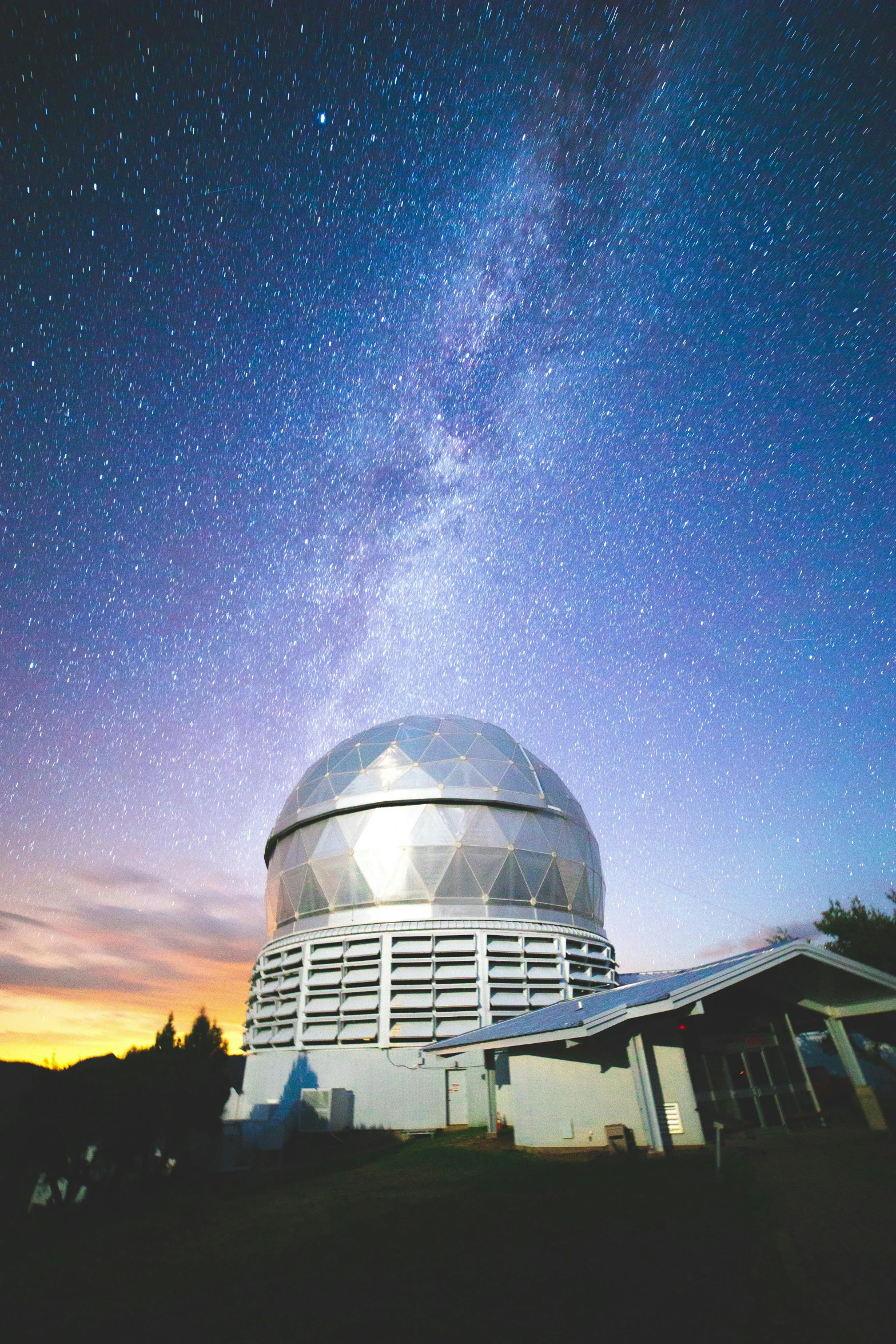 a very large telescope sitting on top of a field under a sky filled with stars