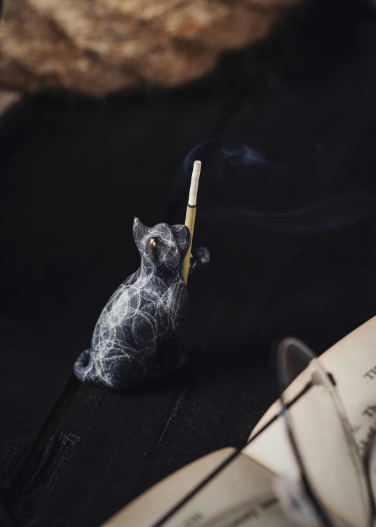 small model dog on a shelf holding a burning match