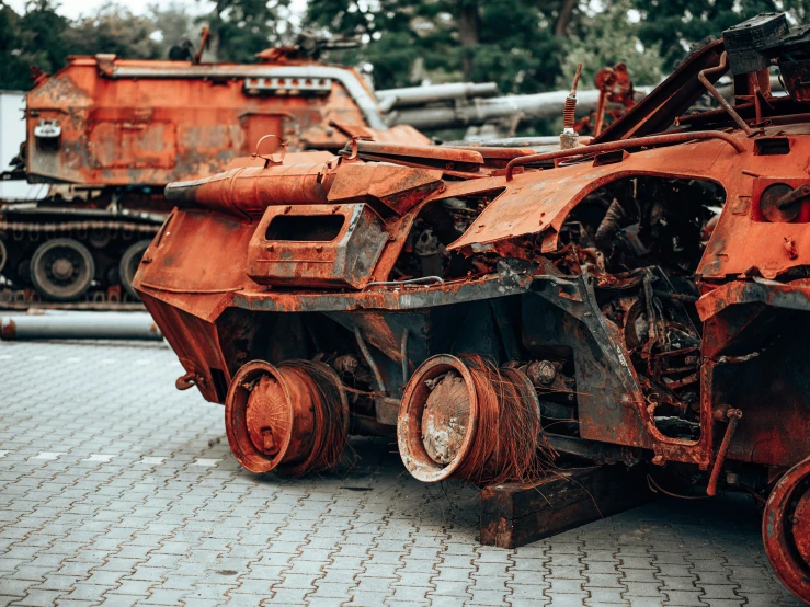 some rusty orange old vehicles sitting in a junkyard