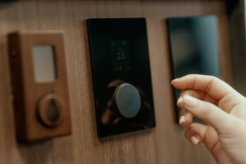 hand pressing on electronic controls on wooden surface