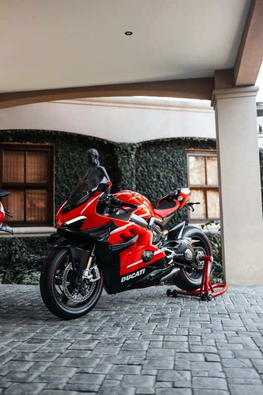 a red motorcycle sitting on a road near a building