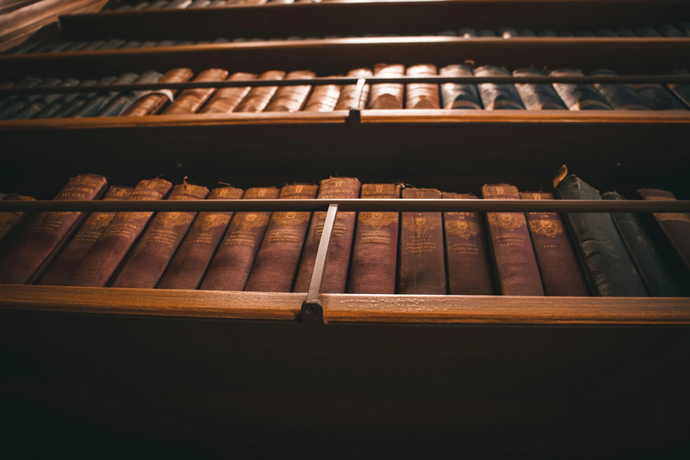 three wooden shelves filled with old books on them