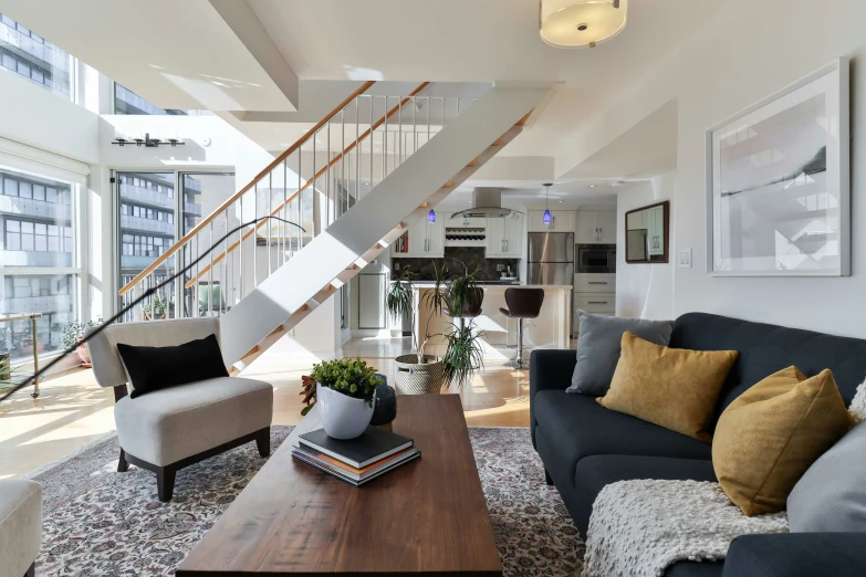 a living room area with couches and a staircase leading up to an upstairs floor level