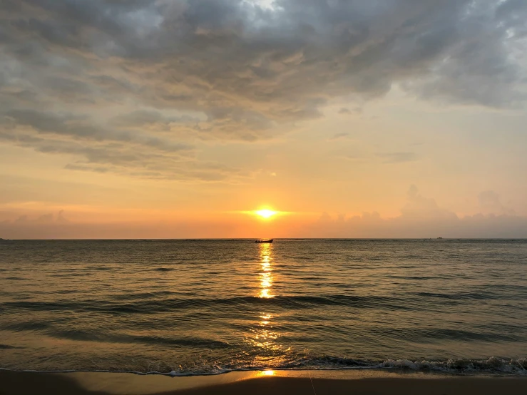 a sunset with the sun rising and some clouds reflected in the water