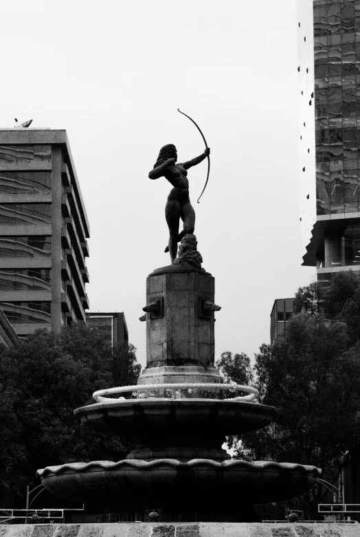 a statue stands near some high rise buildings in a city