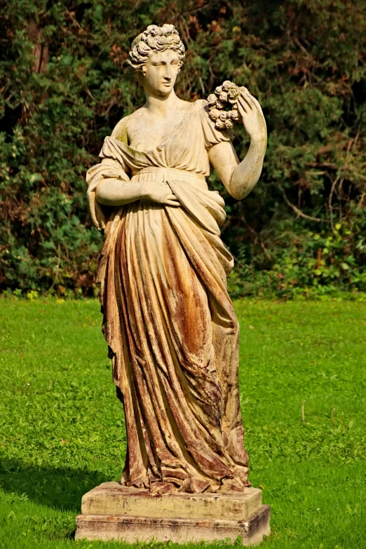 a statue in a grassy area with trees behind it
