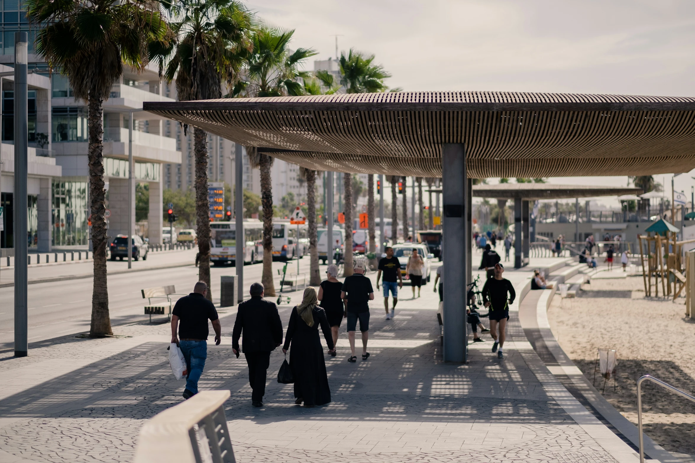 a group of people walk down a paved walkway lined with palm trees